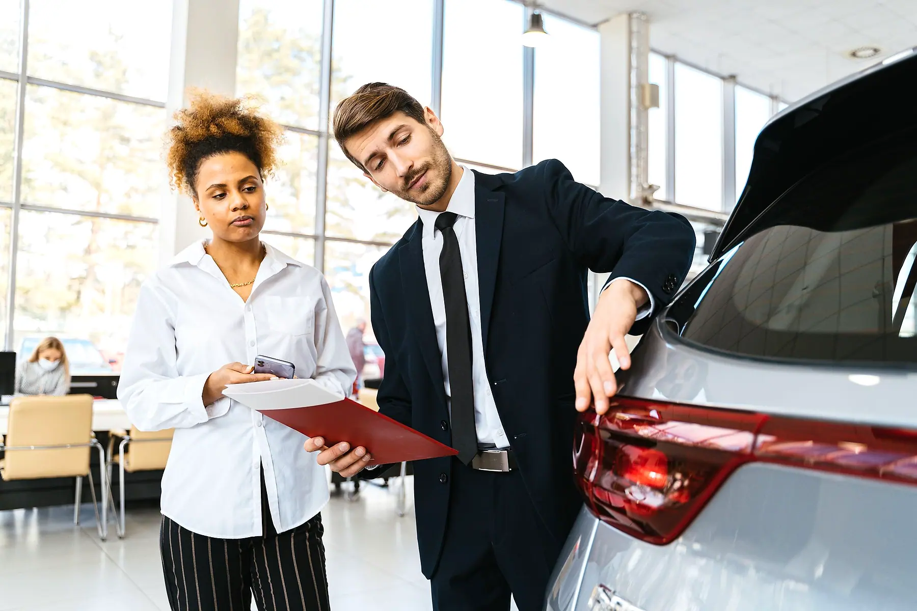 A car salesperson showing a customer around a car on the showroom floor