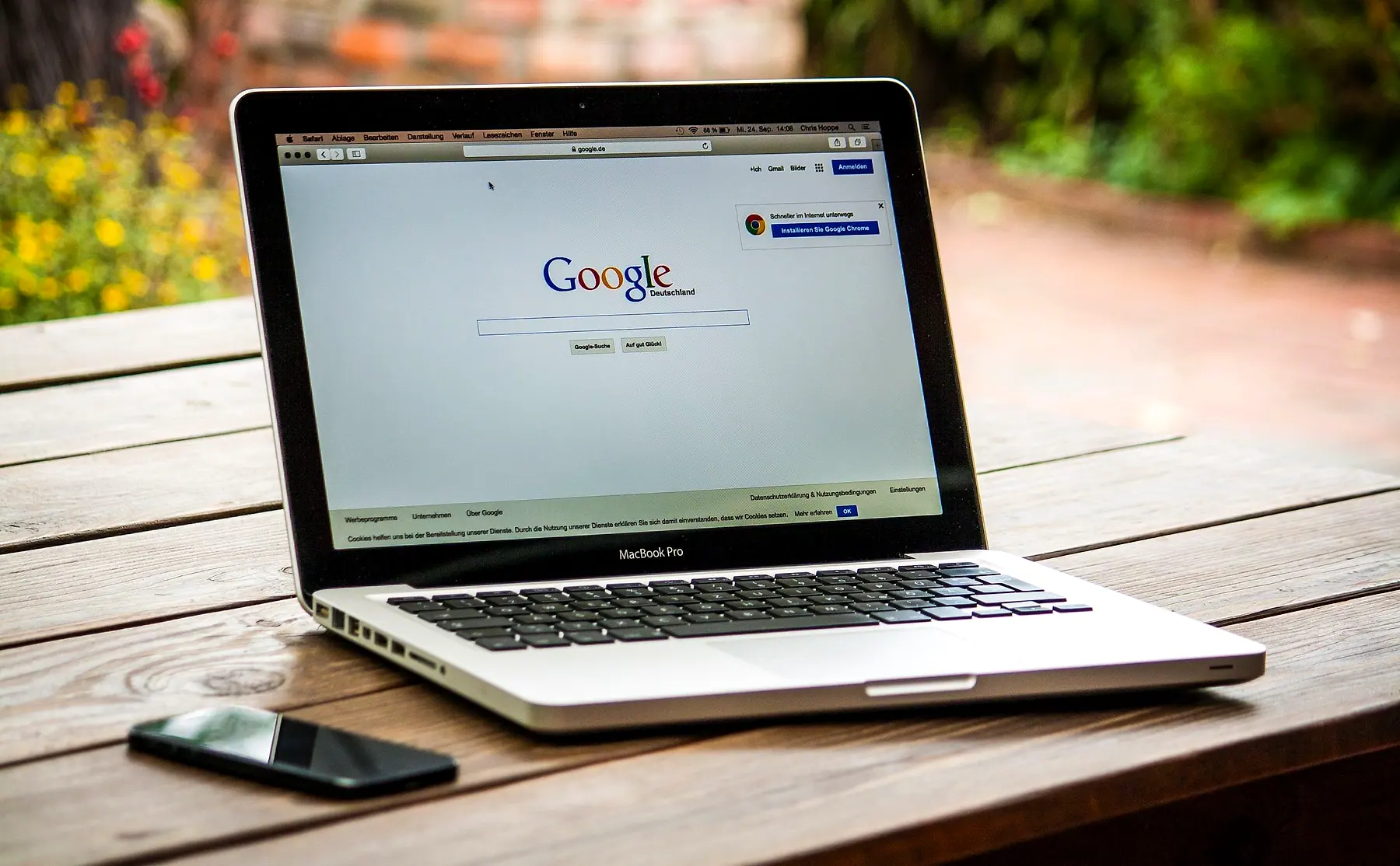 A laptop open on the Google search page on an outdoor wooden table
