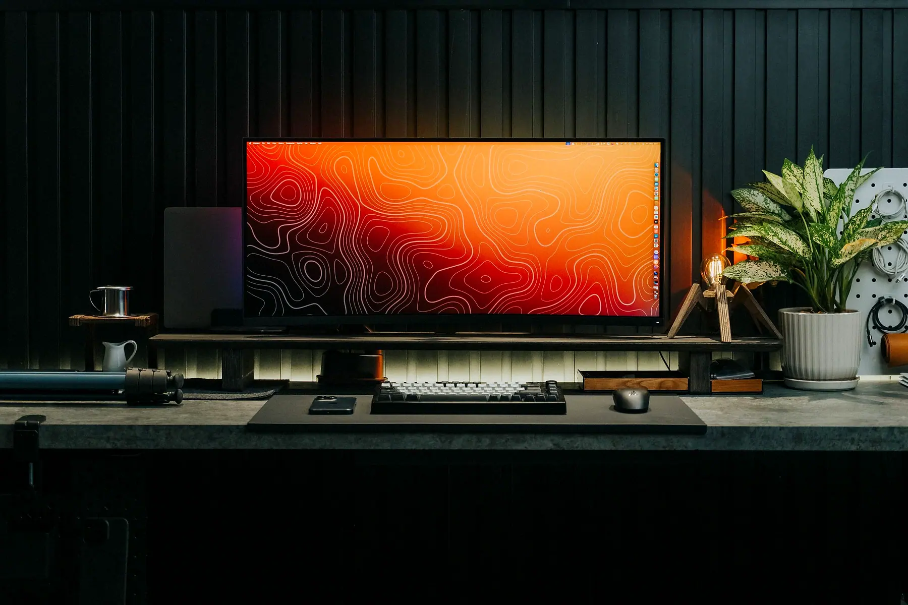 A premium desk setup with an ultrawide monitor against a dark slatted wall